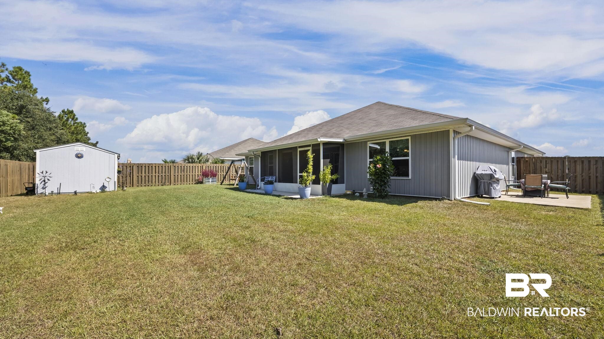 349 Hartenstein Road Foley, AL 36535 - Photo 8 of 32 Back of house with a fenced backyard, a sunroom, and a storage shed