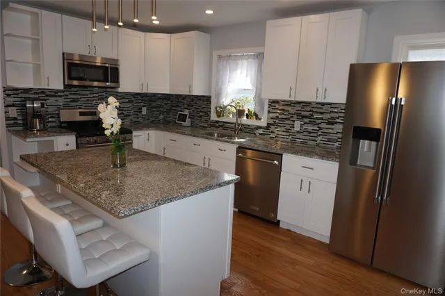 a kitchen with stainless steel appliances granite countertop a sink stove refrigerator and microwave