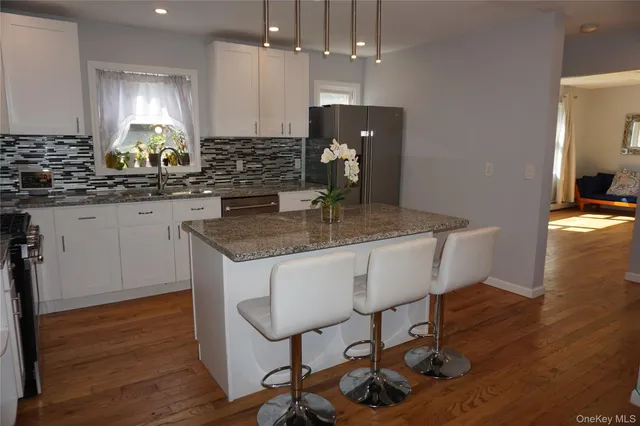 a kitchen with stainless steel appliances granite countertop a sink a stove a dining table and chairs