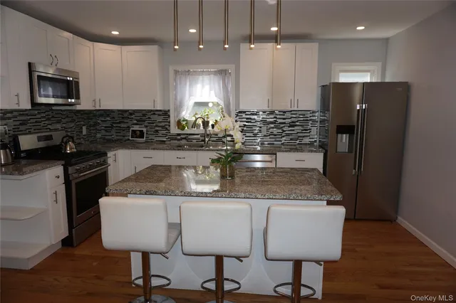 a kitchen with stainless steel appliances granite countertop a kitchen island a stove a refrigerator a sink a dining table and chairs