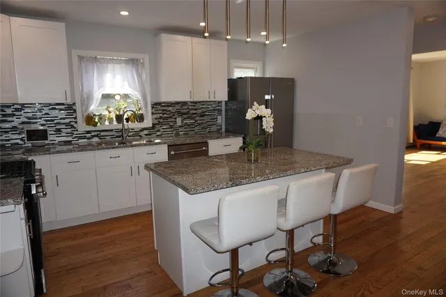 a kitchen with granite countertop kitchen island stainless steel appliances a sink stove and refrigerator