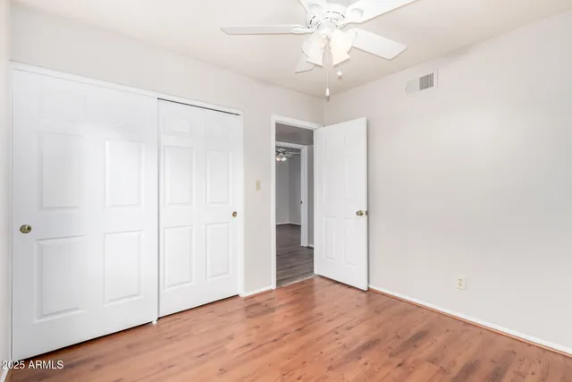 an empty room with wooden floor closet and windows