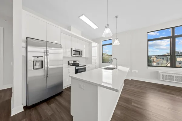 a kitchen with white cabinets and wooden floor
