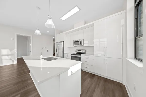 a large white kitchen with sink and refrigerator