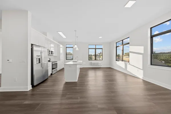 a view of open kitchen with white cabinets and wooden floor