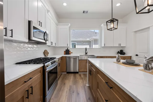 a kitchen with stainless steel appliances granite countertop a sink a stove and cabinets