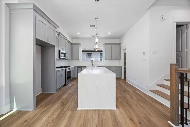 a kitchen with stainless steel appliances granite countertop a refrigerator sink and wooden floor