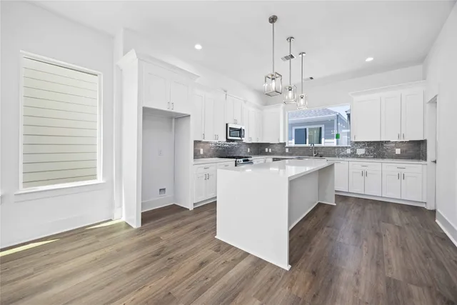 a kitchen with stainless steel appliances granite countertop wooden floors and white cabinets