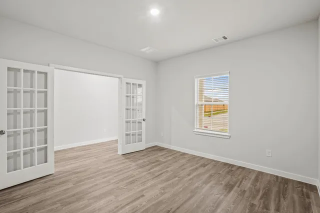 an empty room with wooden floor and windows