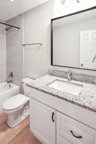 a bathroom with a granite countertop toilet sink and mirror