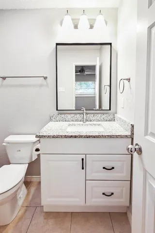 a bathroom with a granite countertop toilet sink and mirror