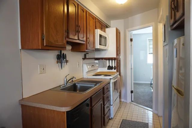 a kitchen with stainless steel appliances granite countertop a sink a stove and a refrigerator with wooden cabinets