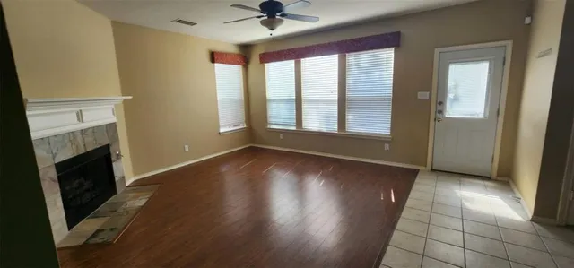 an empty room with wooden floor fireplace and windows