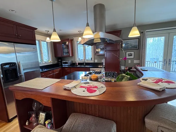 a kitchen with stainless steel appliances wooden floors wooden cabinets a dining table and chairs
