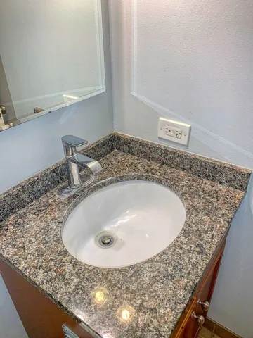 a bathroom with a granite countertop sink and mirror