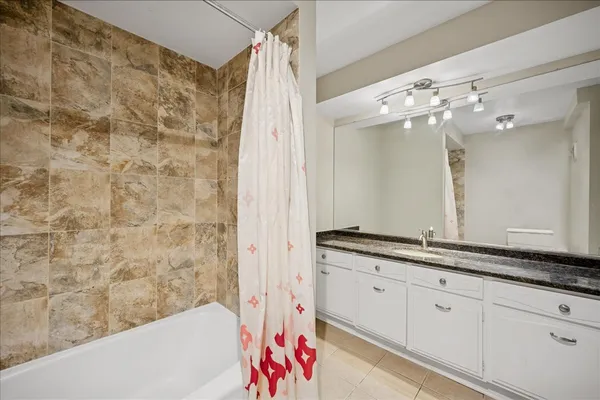 a bathroom with a granite countertop sink a mirror and a bathtub