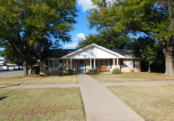 a front view of a house with a yard and trees