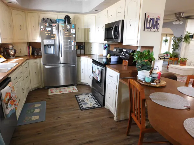 a kitchen with stainless steel appliances granite countertop a refrigerator a stove a sink dishwasher and microwave with wooden floor