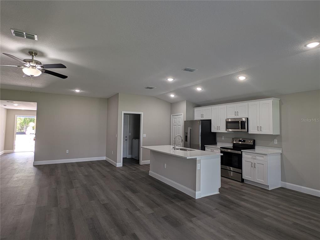 1225 Vanderway Lane Lady Lake, FL 32159 - Photo 11 of 13 a open kitchen with kitchen island a stove a sink dishwasher and a refrigerator with wooden floor