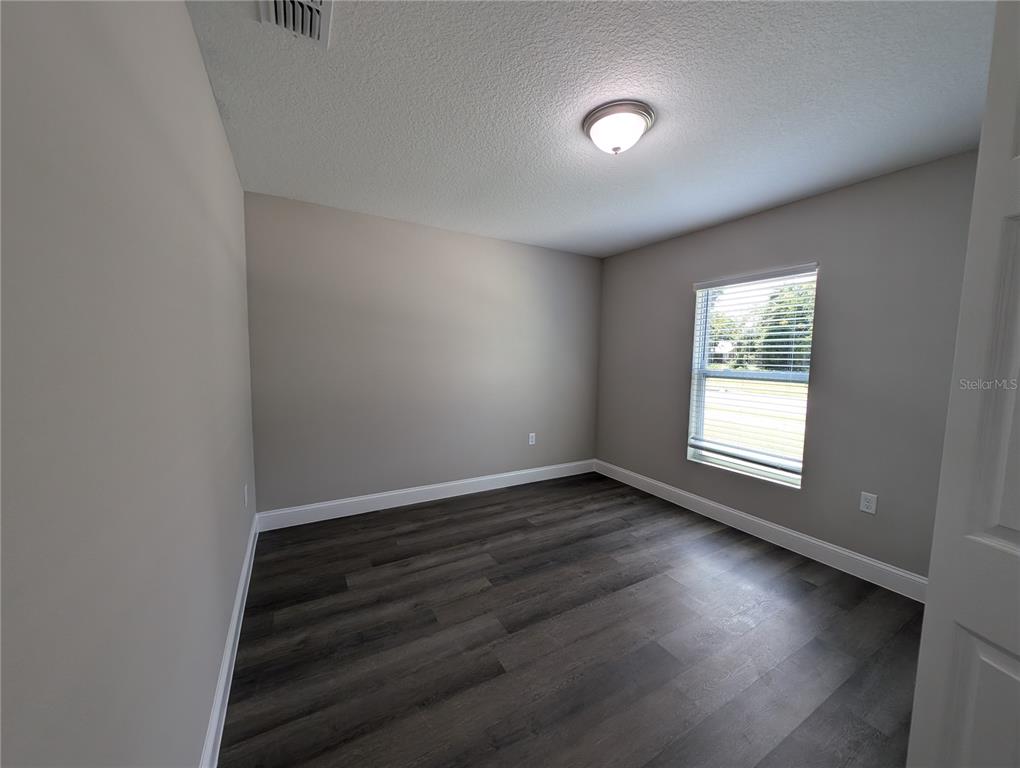 1225 Vanderway Lane Lady Lake, FL 32159 - Photo 6 of 13 a view of an empty room with wooden floor and a window