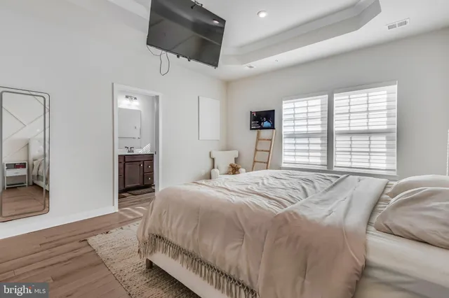 a spacious bedroom with a bed a flat screen tv and window