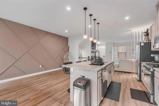 a kitchen with stainless steel appliances granite countertop a sink a stove and a wooden floors