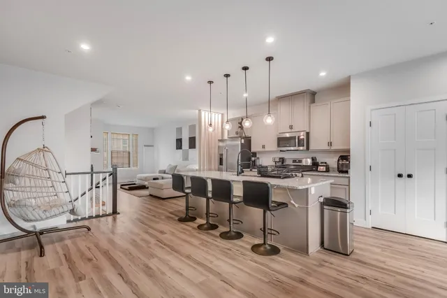 a kitchen with stainless steel appliances kitchen island granite countertop a table chairs refrigerator and sink