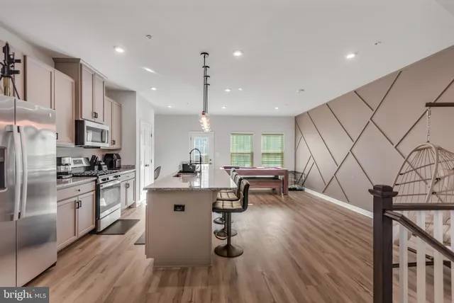 a kitchen with stainless steel appliances a refrigerator a stove a sink dishwasher a oven with white cabinets and wooden floor