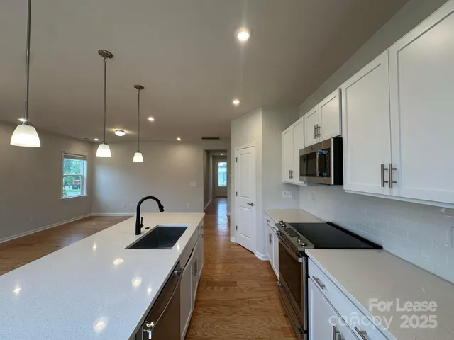 a kitchen with stainless steel appliances a sink a stove and a wooden floors