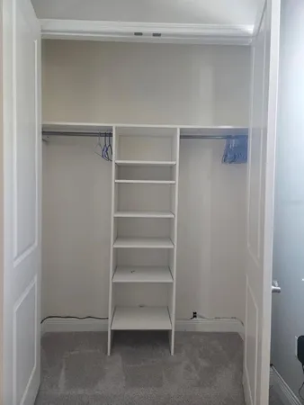 a utility room with stainless steel appliances white cabinets and a refrigerator