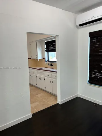 an empty room with a wooden floor and potted plant
