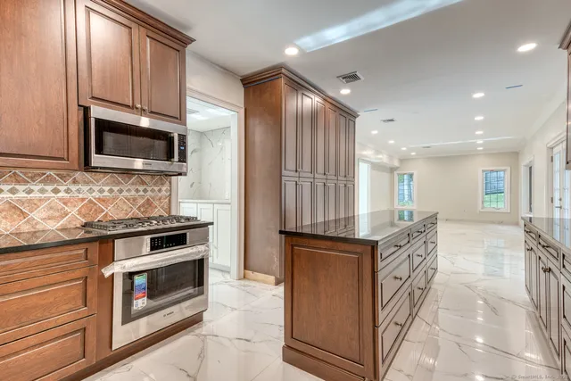 a kitchen with stainless steel appliances kitchen island granite countertop a stove top oven a sink and a microwave