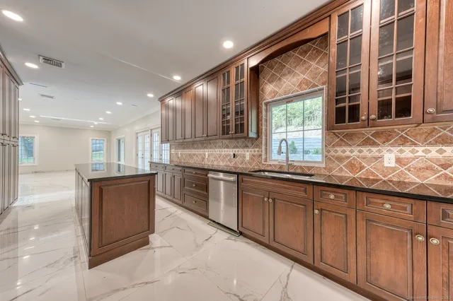 a large kitchen with kitchen island granite countertop a large window and a counter space