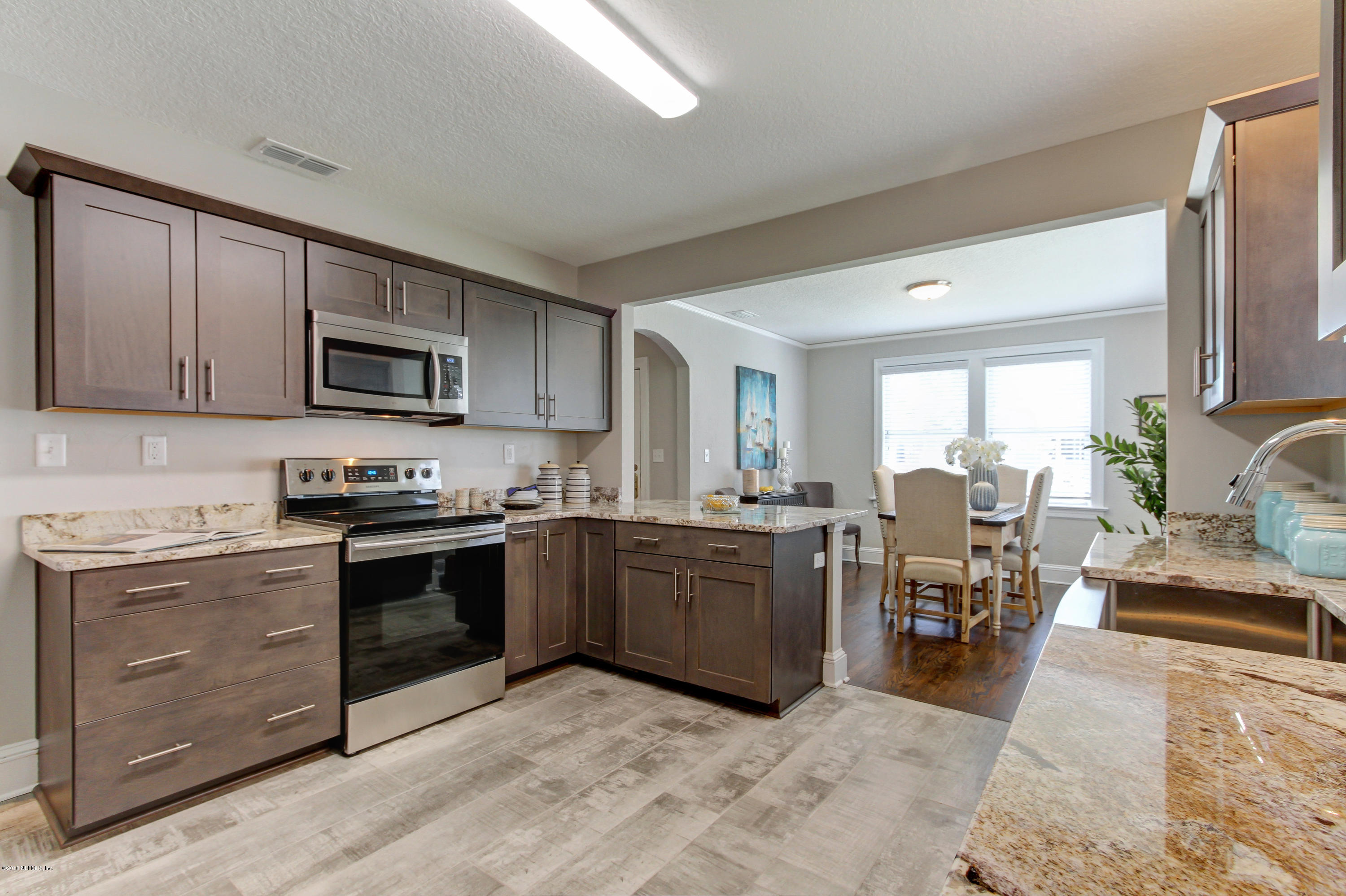 1026 Riviera Street Jacksonville, FL 32207 - Photo 4 of 48 a kitchen with stainless steel appliances granite countertop a stove top oven a sink dishwasher a dining table and chairs with wooden floor