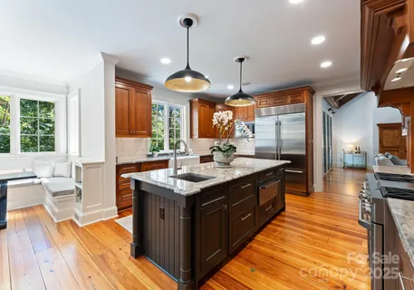 a spacious kitchen with stainless steel appliances granite countertop a sink a stove and a wooden floors