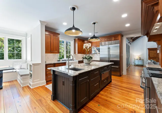 a spacious kitchen with stainless steel appliances granite countertop a sink a stove and a wooden floors