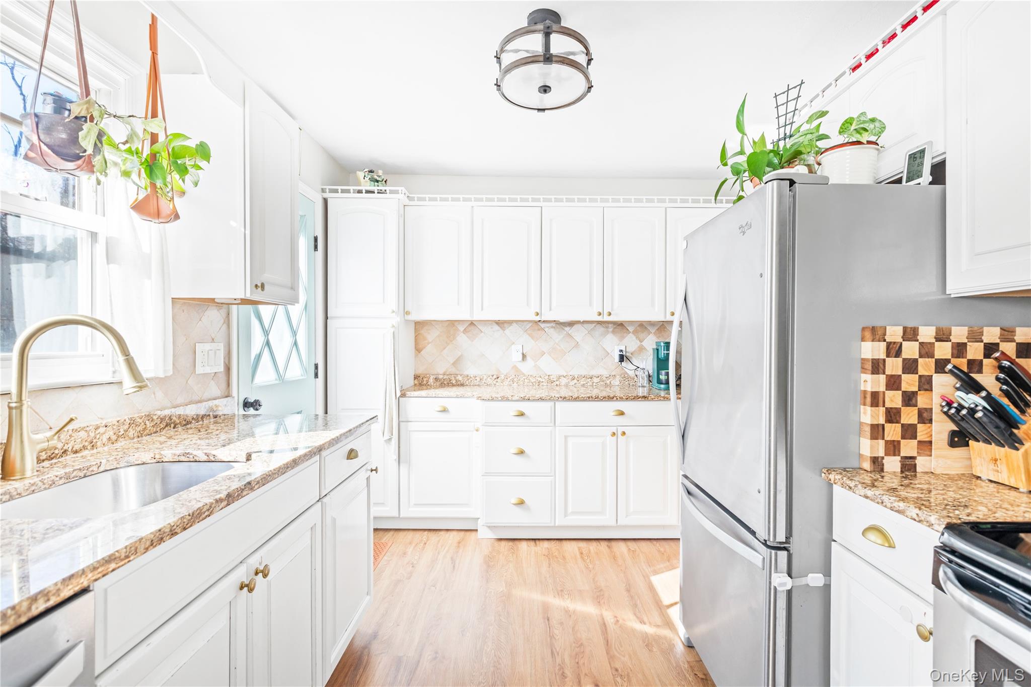 193 Maple Road Wading River, NY 11792 - Photo 8 of 17 a kitchen with granite countertop a white refrigerator a sink dishwasher and white cabinets with wooden floor