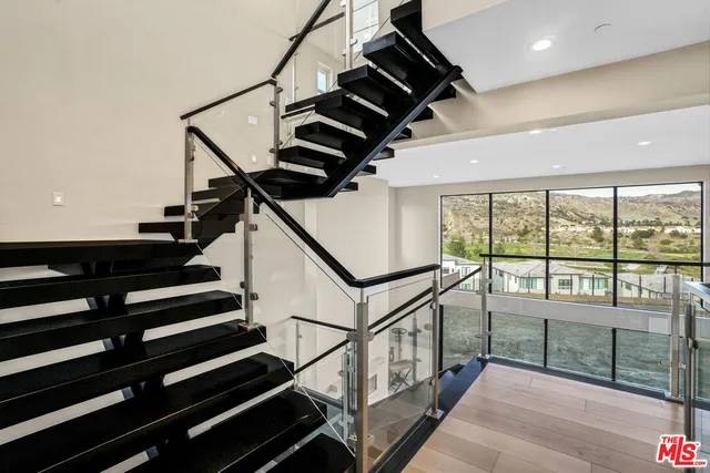 a view of an empty room with wooden floor and windows