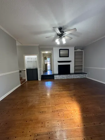 a view of a livingroom with a fireplace a ceiling fan and kitchen view