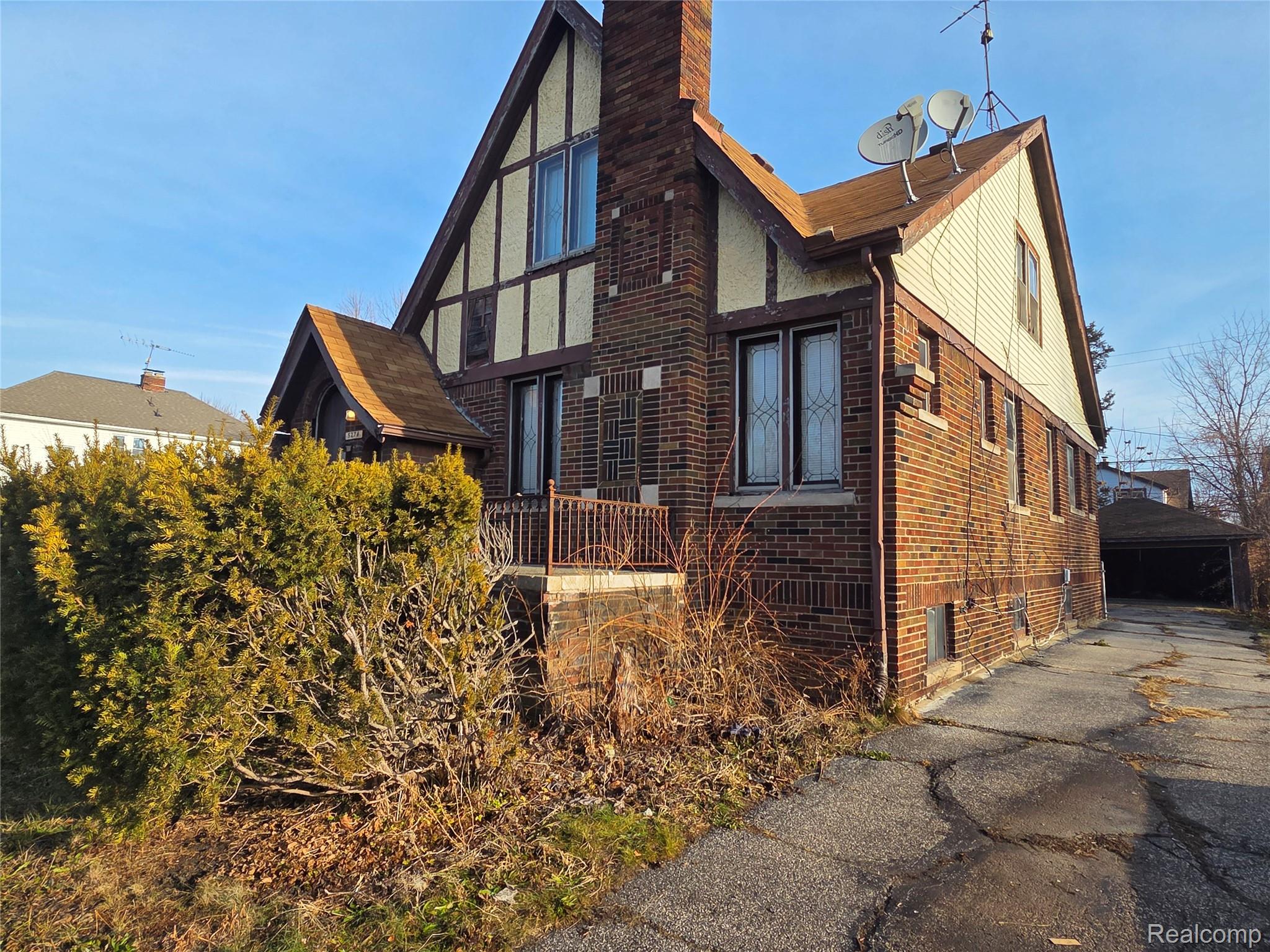 5274 Nottingham Road Detroit, MI 48224 - Photo 2 of 18 View of side of home with brick siding, a chimney, a detached garage, an outdoor structure, and stucco siding