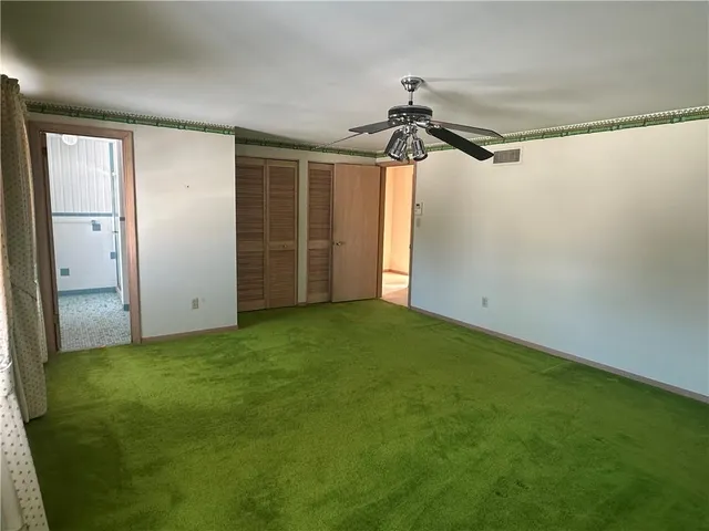 an empty room with closet and a chandelier fan