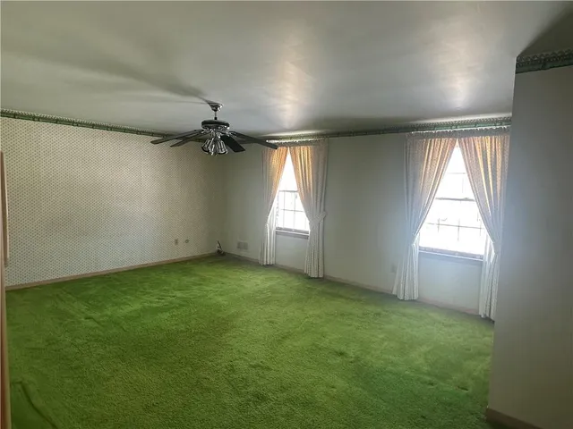 en empty room with windows and a ceiling fan