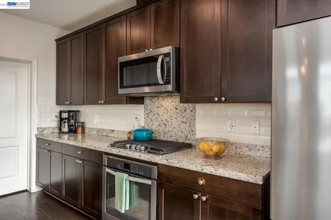 a kitchen with stainless steel appliances granite countertop a stove a microwave a sink and cabinets