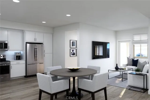 a living room with stainless steel appliances a dining table and a refrigerator