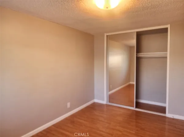 a view of an empty room with wooden floor and closet