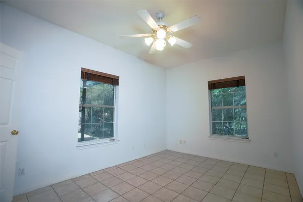 an empty room with windows and fan