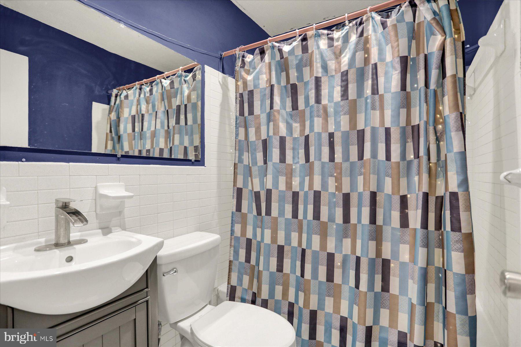 959 Elm Road Baltimore, MD 21227 - Photo 14 of 27 a bathroom with a sink a toilet and shower curtain