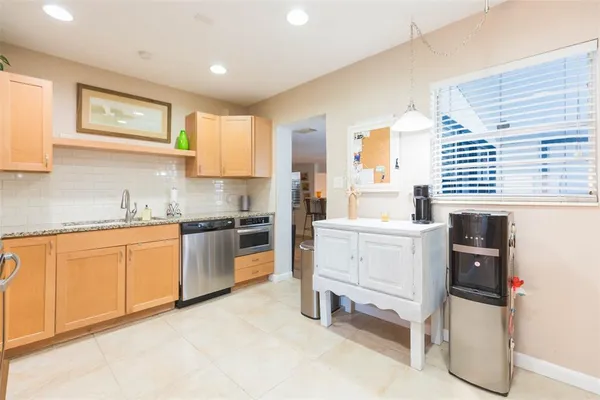 a kitchen with stainless steel appliances granite countertop white cabinets a sink a stove a window and white kitchen
