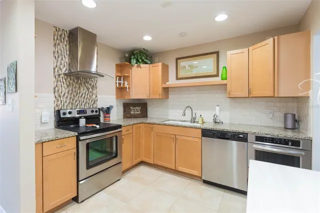 a kitchen with stainless steel appliances granite countertop a refrigerator a stove a sink and a microwave