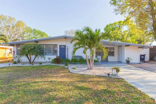 a view of a house with a yard and palm trees